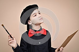 Young painter with red bow tie and black shirt and cap holding paint brush and art palette