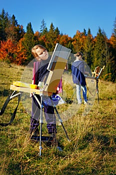 Young painters at work near waterfall