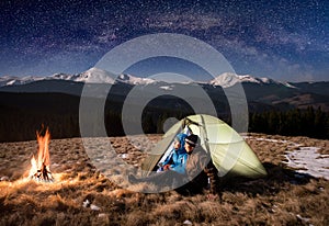 Young pair tourists enjoying in the camping at night under beautiful night sky full of stars and milky way