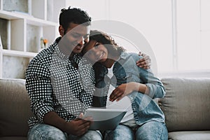 Young Pakistani Man with Pregnant Wife on Sofa.