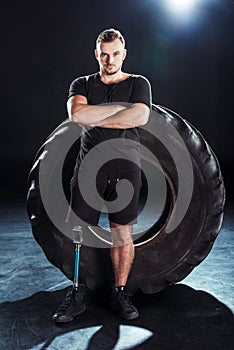 young paralympic sportsman with leg prosthesis and arms crossed leaning