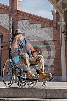 Young paralyzed man in a wheelchair frustrated in front of some stairs