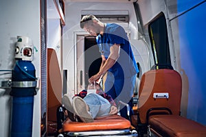 Young paramedic giving an oxygen mask to his female patient in an ambulance car