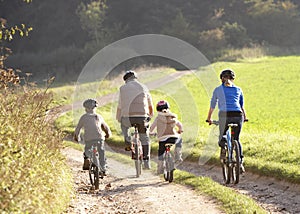 Young parents with children ride bikes in park photo