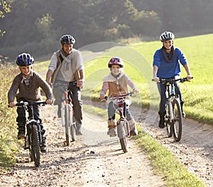 Young parents with children ride bikes in park