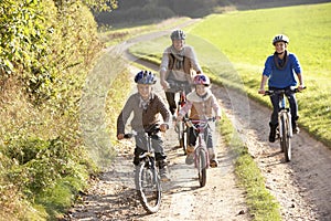 Young parents with children ride bikes in park