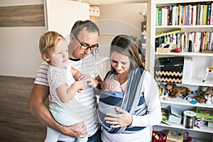 Young parents with children in sling and baby carrier