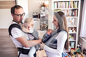 Young parents with children in sling and baby carrier photo