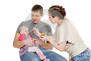 Young parents feed baby.