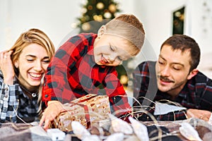 Young parents giving a Christmas present to little son at Chrismas morning in bed.