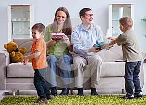 Young parents giving out Christmas gifts at home