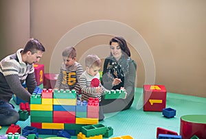 Young parents and kids having fun at childrens playroom