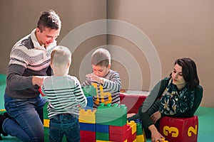 Young parents and kids having fun at childrens playroom