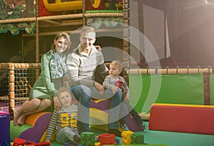 Young parents and kids having fun at childrens playroom