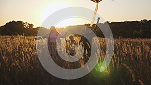 Young parents with little cute girl holds hands of each other running among summer meadow at sunset. Mother and father