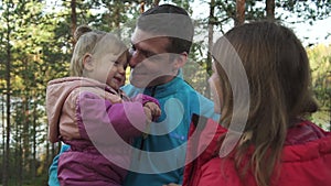 young parents with little daughter in forest or park outdoor portrait