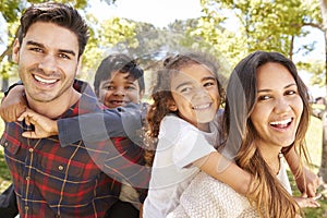 Young parents piggybacking their two kids outdoors