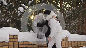 Young parents playing with his son in the park. Baby touching snow-covered pine branch. A child enjoys his first winter