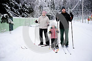 Young parents and their daughter do Nordic skiing