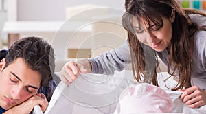 Young parents with their newborn baby near bed cot