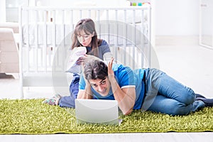 The young parents with their newborn baby sitting on the carpet