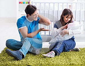 Young parents with their newborn baby sitting on the carpet