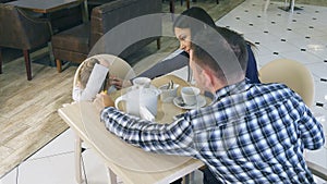 Young parents try to calm their little frustrated daughter in cafe.