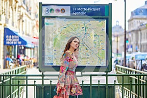 Young Parisian woman near the subway plan, looking for the direction