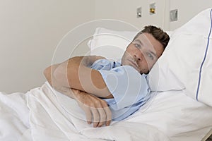 Young patient man lying at hospital bed resting tired looking sad and depressed worried