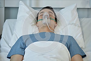 Young patient in oxygen mask lying in hospital