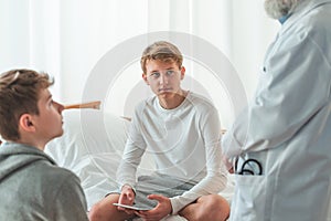 Young patient is sitting cross-legged on a hospital bed during hospitalization