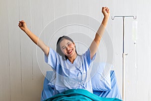 Young patient woman lying at hospital bed with saline sign for cheerful. Drop of saline solution to help patient