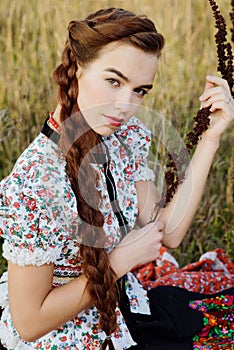 Young peasant woman, dressed in Hungarian national costume, posing over nature background