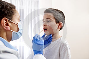 Young pediatrician examining little boys throat to diagnose his illness