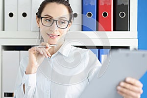 Young pensive businesswoman in glasses is studying financial documents