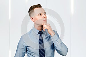Young pensive man businessman think, dressed in blue shirt and tie