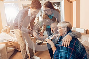 Young people came to visit the older man and woman in a nursing home.