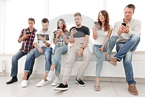 Young people in casual clothes using gadgets