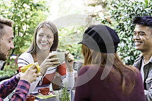 Young people drinking cappuccino and espresso coffee at cafe bar garden - Happy friends talking and having fun together at hostel