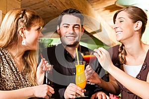 Young people drinking cocktails in bar