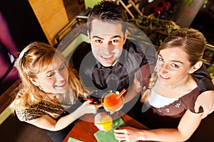 Young people drinking cocktails in bar or restaurant