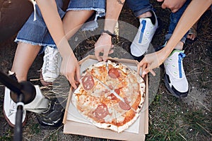 Young people eating pizza smoking shisha outside
