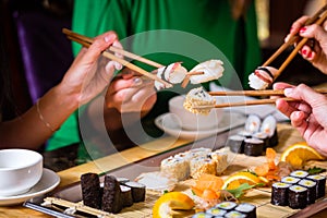 Young people eating sushi in restaurant