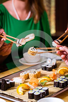 Young people eating sushi in restaurant