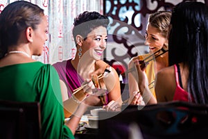 Young people eating sushi in restaurant