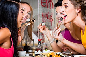 Young people eating sushi in restaurant