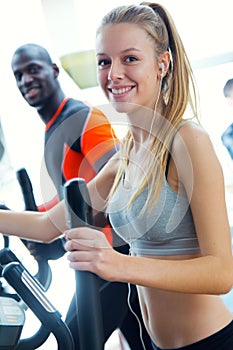 Young people with elliptic machine in the gym.