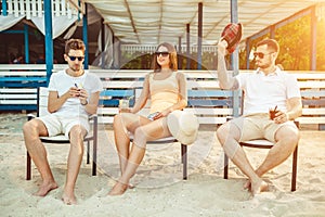 Young people enjoying summer vacation sunbathing drinking at beach bar