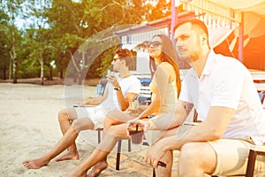 Young people enjoying summer vacation sunbathing drinking at beach bar