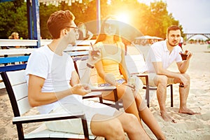 Young people enjoying summer vacation sunbathing drinking at beach bar